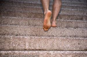 Des pieds et jambes nus montent un escalier - vu par derrier.